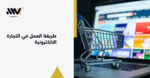 عربة تسوق رقمية فوق لوحة مفاتيح لابتوب أمام متجر إلكتروني، تشرح طريقة العمل في التجارة الالكترونية وإدارة الأنشطة التجارية.